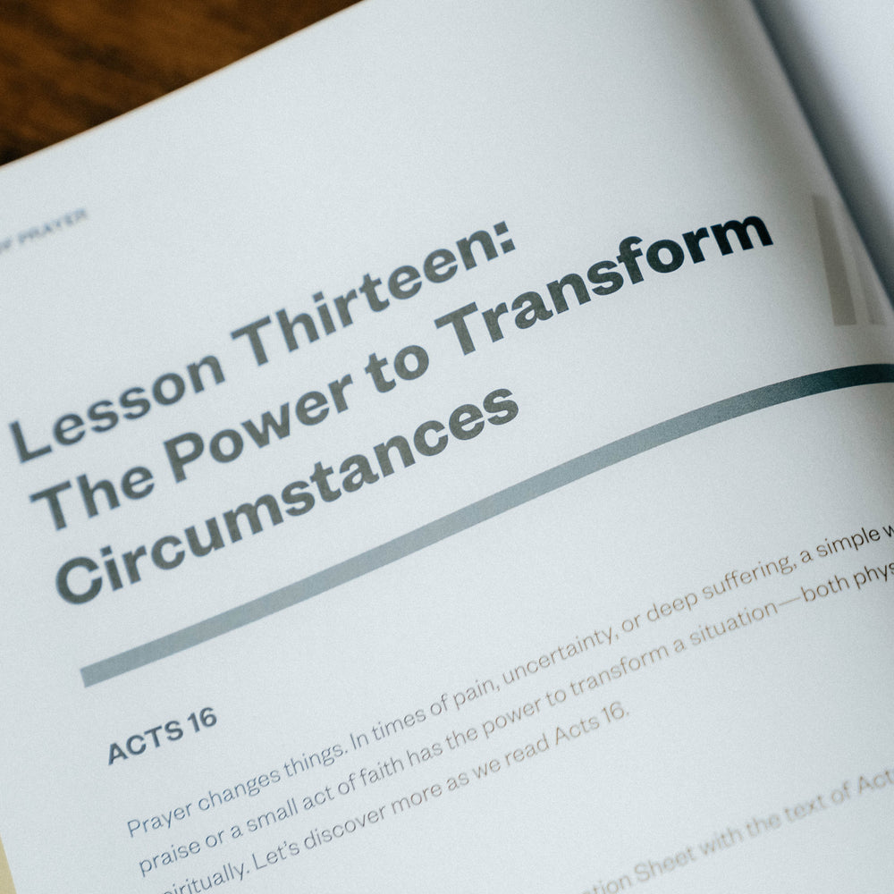 Open book with a page titled 'Lesson Thirteen: The Power to Transform Circumstances' on a wooden surface.